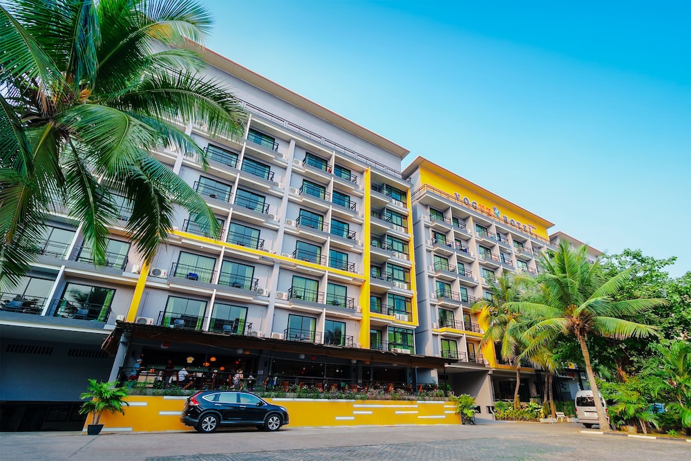 Vogue Pattaya Hotel - Yellow and white exterior with palm trees